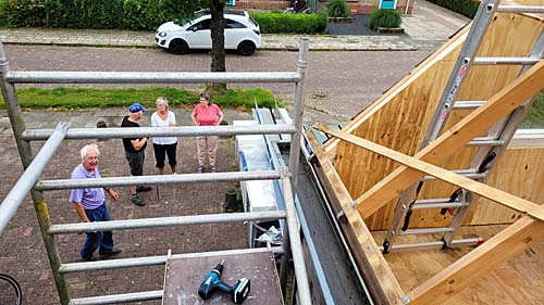 Verbouw schuur Doarpskeamer Akkrum-NesDe schuur naast de Doarpskeamer Akkrum-Nes is tijdens de zomermaanden ingrijpend verbouwd. De ruimte wordt geschikt gemaakt voor activiteiten, zoals timmer- en schilderscursussen en bloemschikken. Een ploeg vrijwilligers heeft in wisselende samenstelling de klus geklaard.Het grotendeels vrijstaande gebouw is straks volledig geïsoleerd. Vloeren en wanden zijn van isolatieplaten voorzien en met hout afgetimmerd. Geïsoleerde dakplaten zijn in twee dagen tijd gelegd. Het aftimmeren vindt de komende maanden plaats. Coördinator Roland van der Starre heeft in de afgelopen maanden heel wat werk verzet om de vrijwilligersploeg op sterkte te houden. Zelfs in zijn tennistrainingsploegje ronselde hij helpers. Wim Wouters, Fred Zondervan, Aize Wijnstra hebben onder andere de vloer en de wanden geïsoleerd en van nieuwe beplating voorzien.Het bouwteam kreeg vanwege de corona ook te maken met stijgende kosten voor materiaal en kampte met een soms problematische levering ervan. Harde wind zorgde ook een paar keer voor uitstel van het monteren van de dakplaten. De verbouw zorgde niet alleen voor uitgaven, maar ook inkomsten: de oude dakplaten werden op Marktplaats verkocht. Asbestplaten achter de schuur zijn op zorgvuldige wijze weggehaald en naar het gemeentelijk stort gebracht. Op de foto van links naar rechts: Roland van der STarre, Eelco Sixma, Agnes Kruiper en Hennie Sixma.